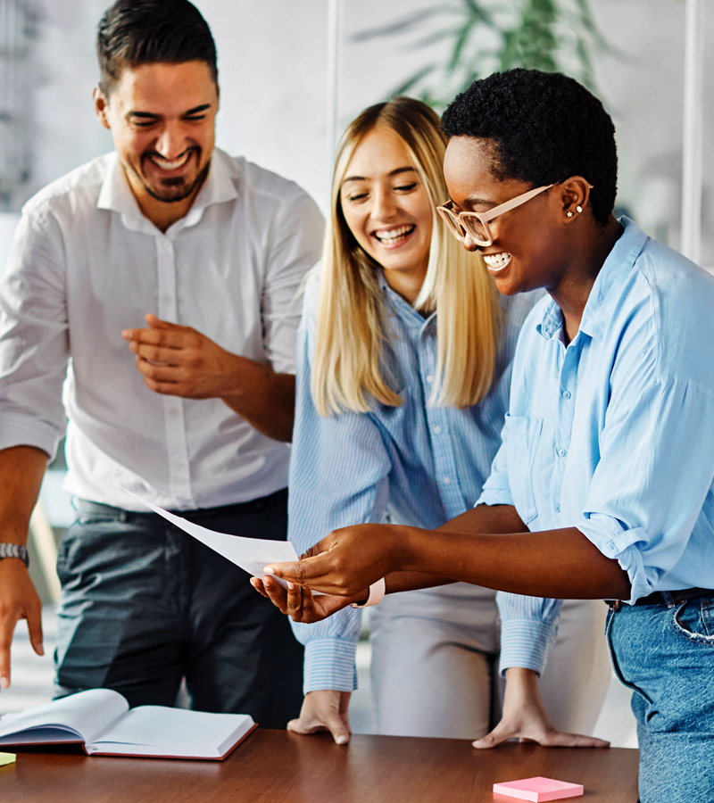 High-performance team of three standing around a table and working together effectively after completing the MCode assessment