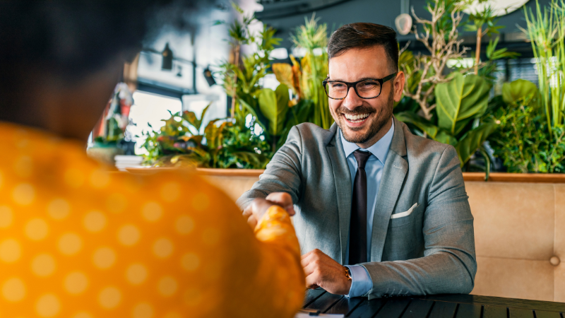 Hiring manager shaking hands with smiling candidate.