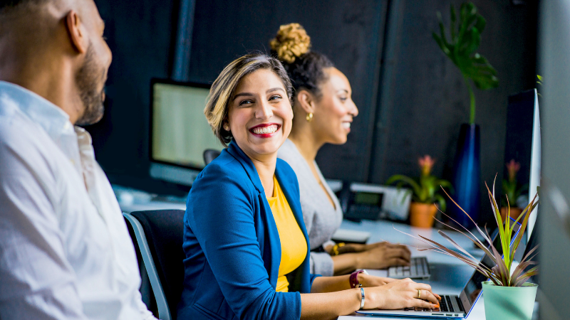 coworker sitting at desk and smiling at colleague
