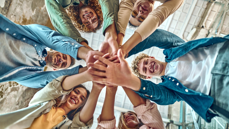 smiling and happy cohesive team all in on a huddle