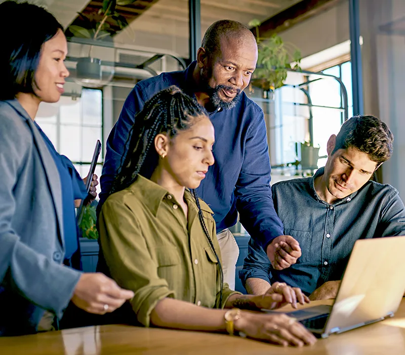 A team leader giving feedback to a member of his team while they are working on their computer.
