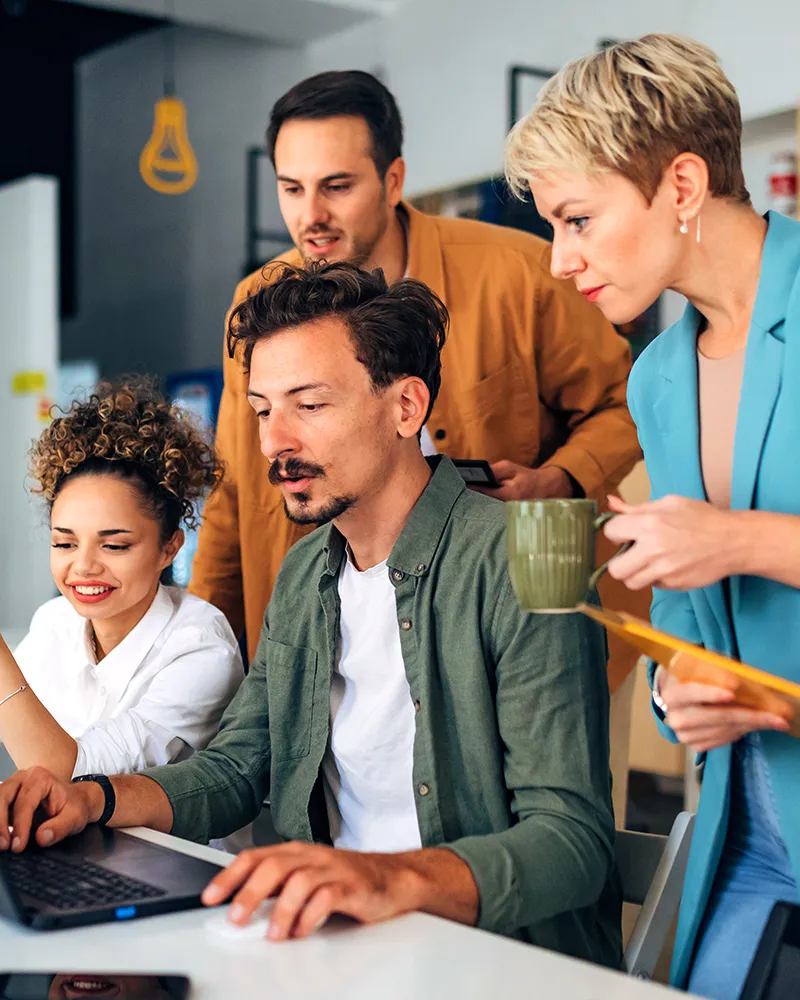 A man showing the people he works with the work he has done on his laptop.