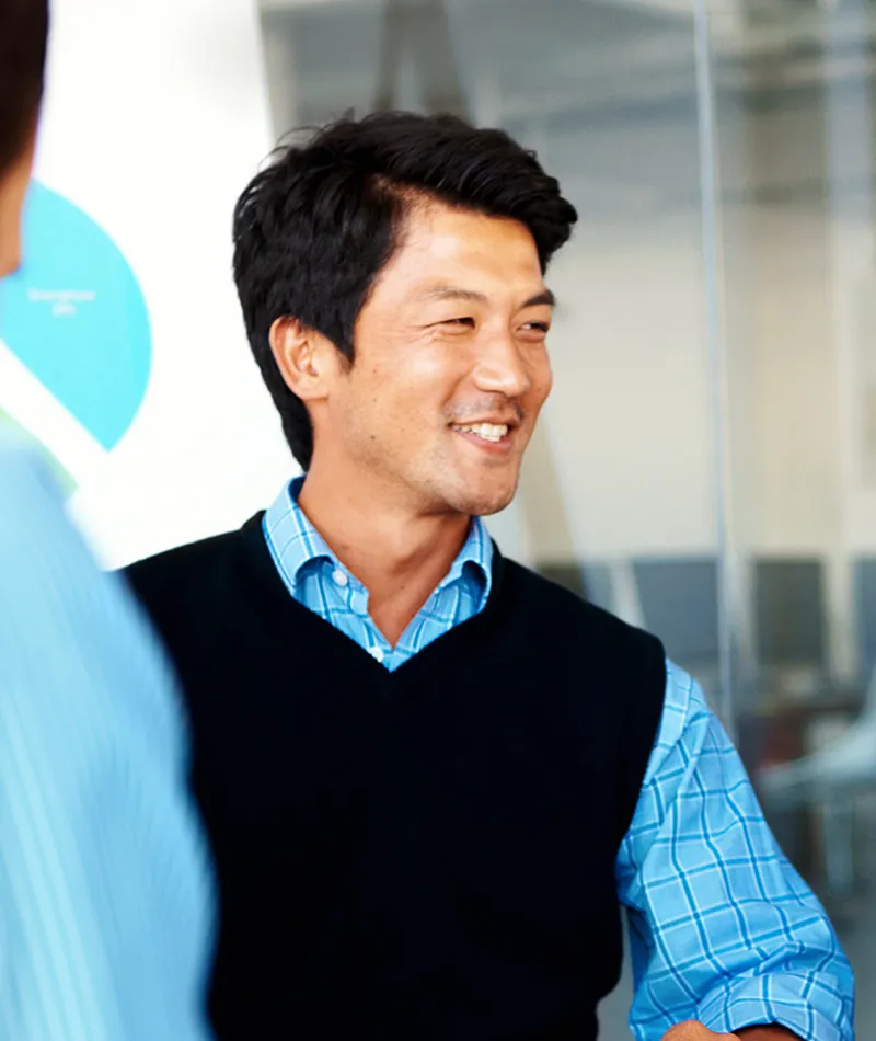A man at work talking to his colleagues and smiling