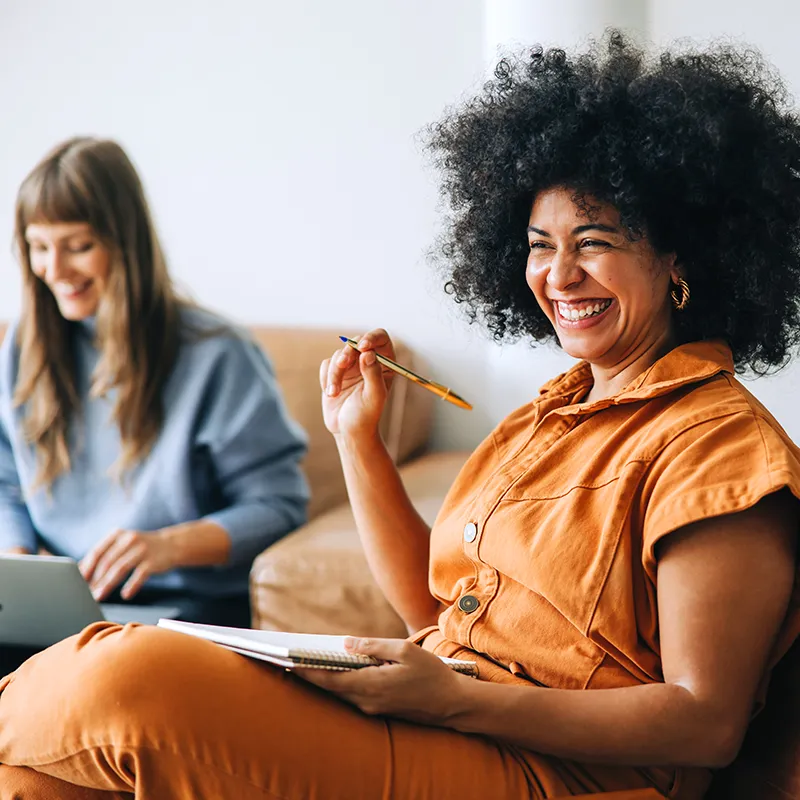 Two women laughing while working together.