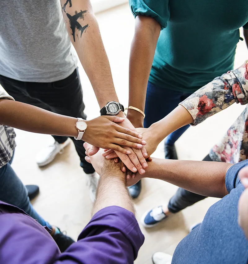 A work team standing in a circle with all hands in the middle